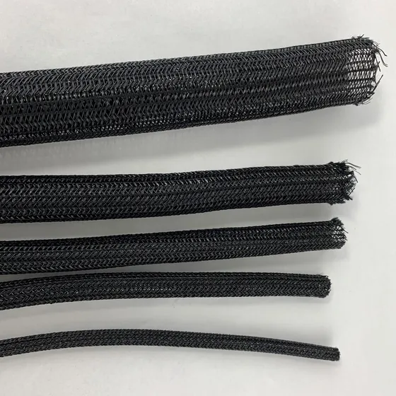 Five diameters of black braided sleeve laid side by side on a white surface, each cut end left open to show the braid structure