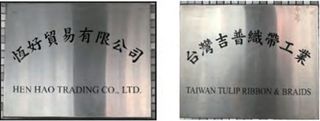 Two brushed-steel company nameplates mounted side by side, engraved 恆好貿易有限公司 / HEN HAO TRADING CO., LTD. and 台灣吉普織帶工業 / TAIWAN TULIP RIBBON & BRAIDS