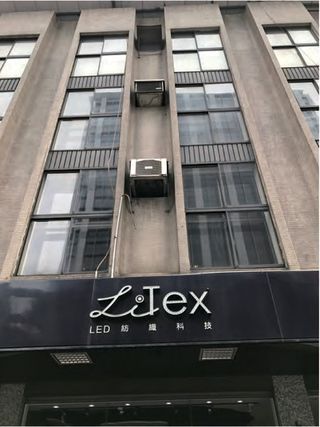 A multi-storey building photographed from street level, with an illuminated shopfront sign reading LiTex above the characters LED 紡織科技
